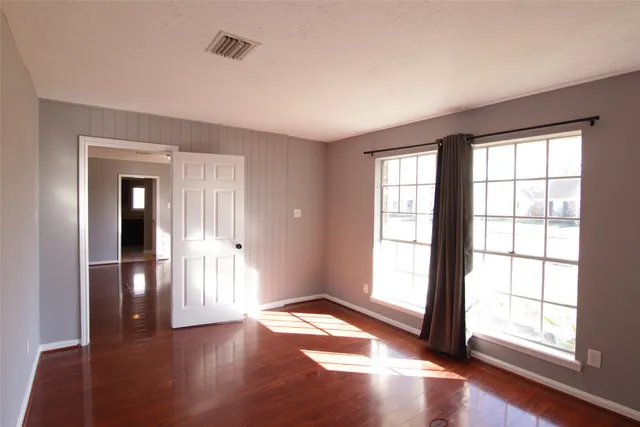 an empty room with wooden floor and windows