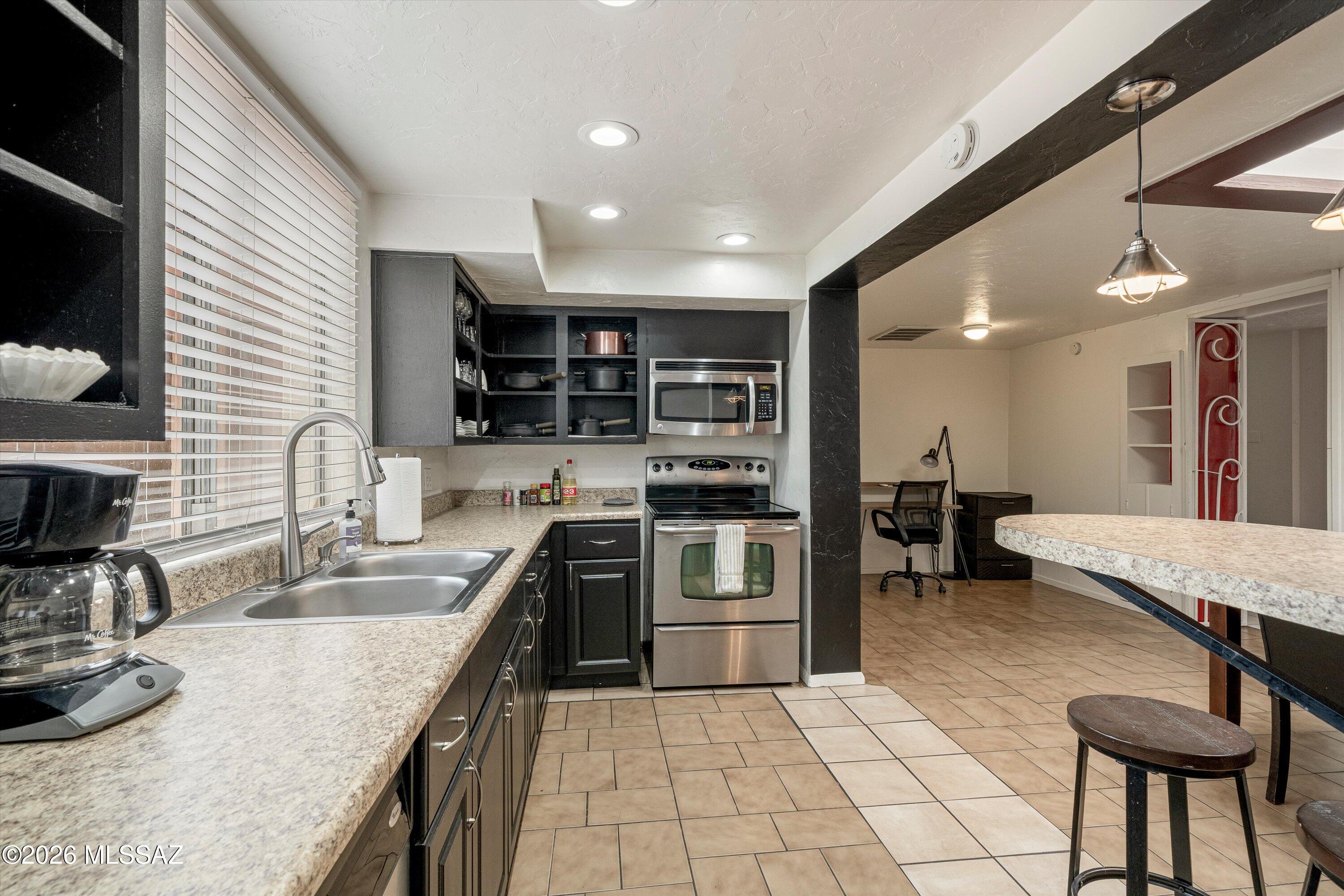2619 East Prince Road Tucson, AZ 85716 - Photo 17 of 50 a kitchen with stainless steel appliances granite countertop a sink counter space cabinets and a stove