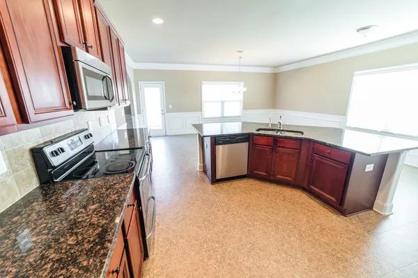 a kitchen with stainless steel appliances granite countertop wooden cabinets a stove top oven a sink and dishwasher