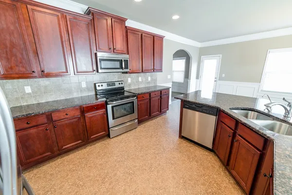 a view of kitchen with kitchen island stainless steel appliances refrigerator sink microwave and cabinets