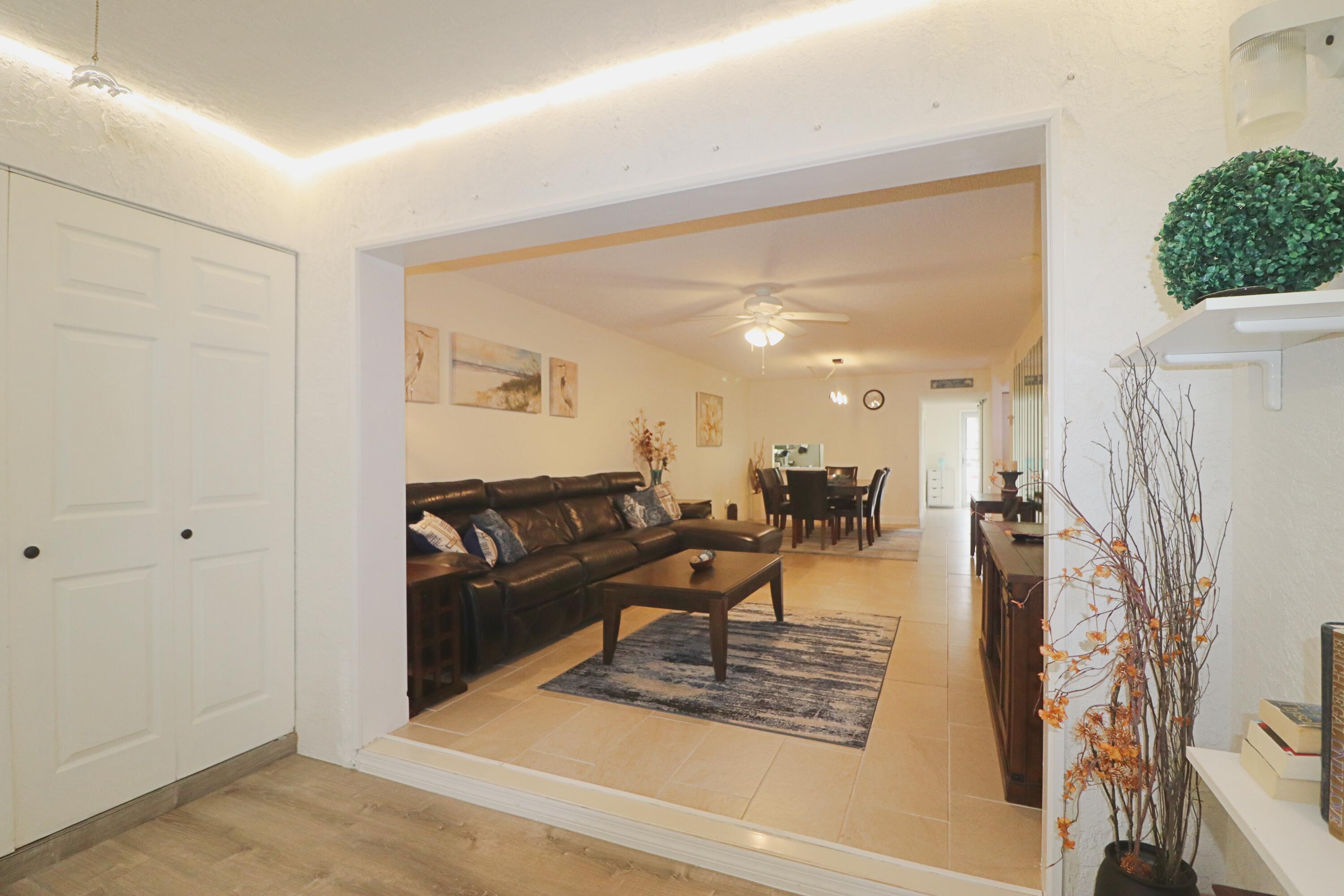 133 Lakes End Drive, Unit E1 Fort Pierce, FL 34982 - Photo 13 of 29 a living room with furniture and a chandelier