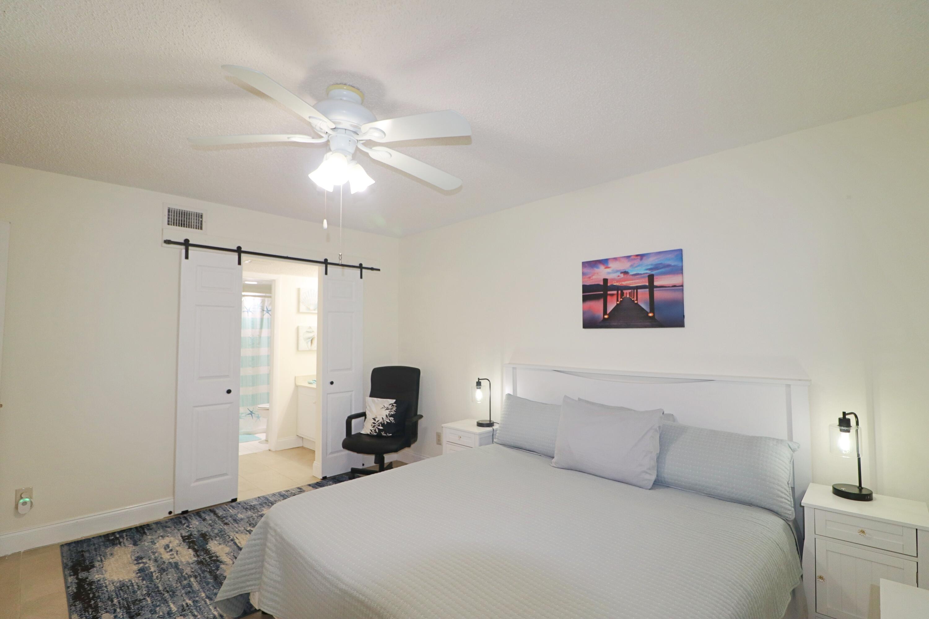 133 Lakes End Drive, Unit E1 Fort Pierce, FL 34982 - Photo 15 of 29 a bedroom with a bed and a chandelier