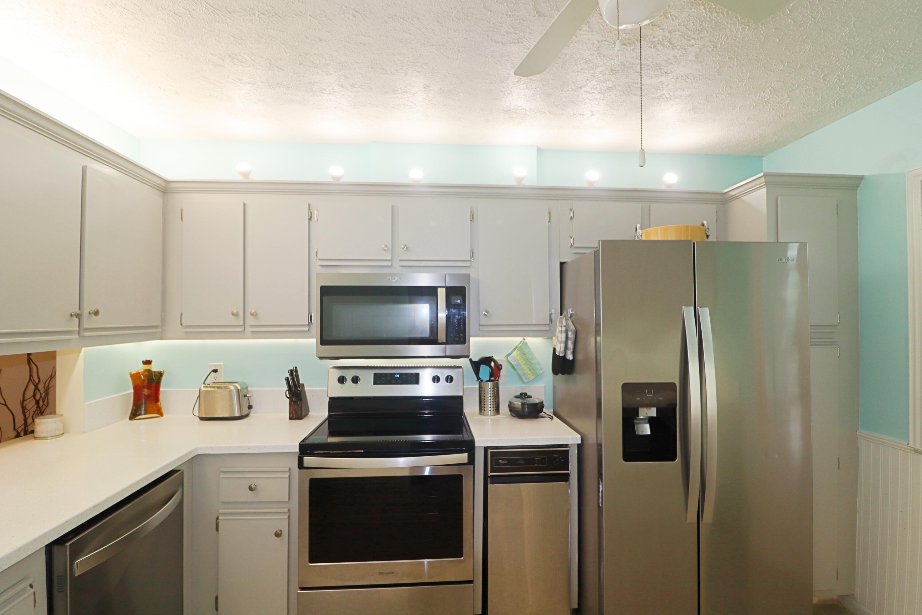 133 Lakes End Drive, Unit E1 Fort Pierce, FL 34982 - Photo 5 of 29 a kitchen with a refrigerator stove and white cabinets