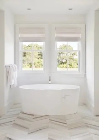 a white bath tub sitting in a bathroom next to a window