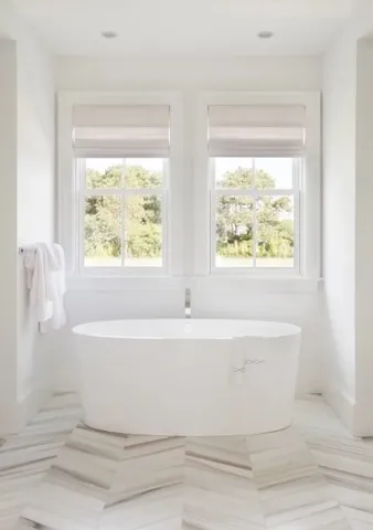 a white bath tub sitting in a bathroom next to a window