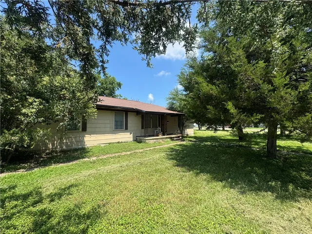 a view of a house with a yard and a large tree