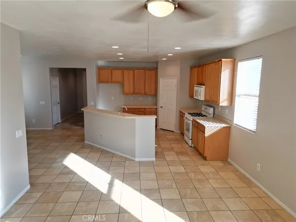 a large white kitchen with cabinets a sink a counter top space and a window