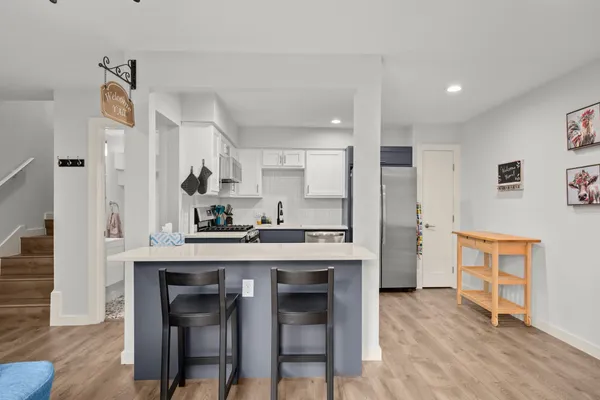 a kitchen with stainless steel appliances wooden floor and chairs
