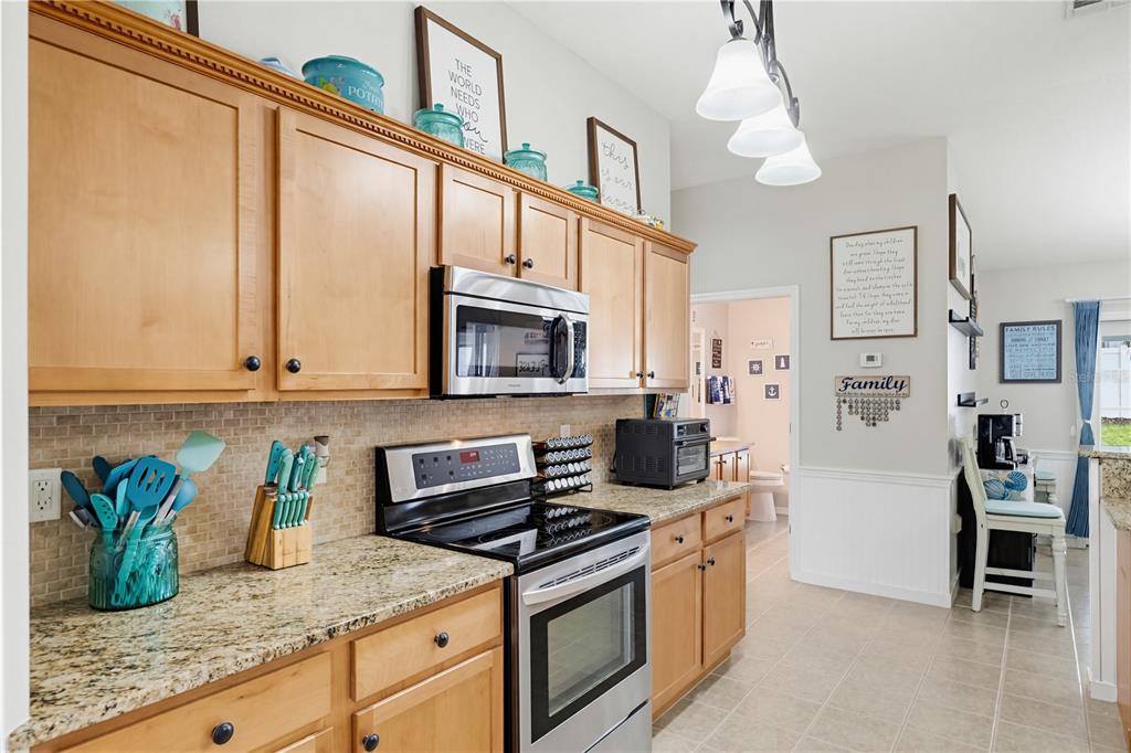 3497 Chadwick Avenue Spring Hill, FL 34609 - Photo 7 of 47 a kitchen with stainless steel appliances granite countertop a stove a sink and a microwave