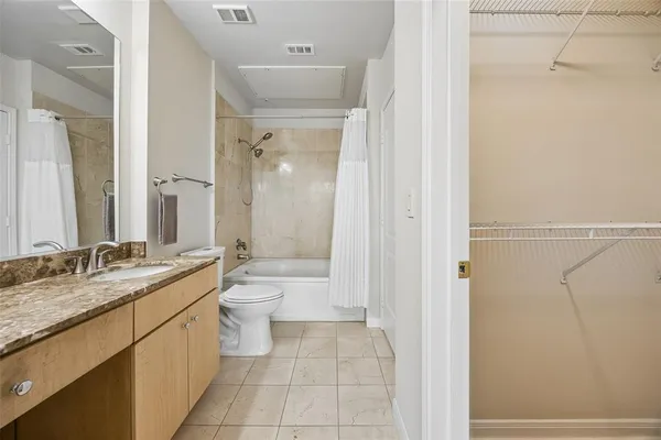 a bathroom with a granite countertop sink toilet a large mirror a shower and a bathtub