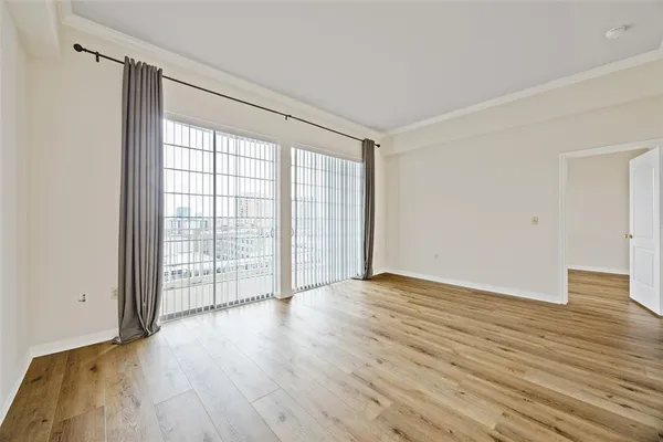 a view of an empty room with wooden floor and a window
