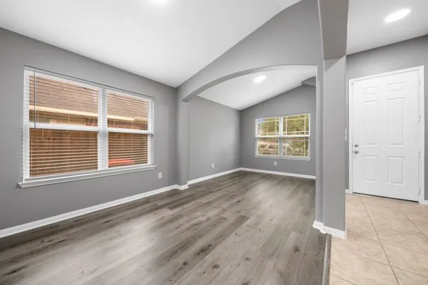 an empty room with wooden floor and windows