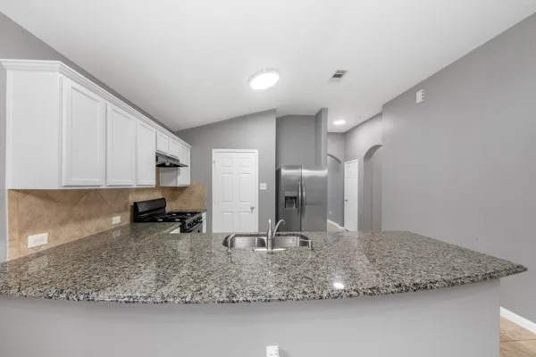a view of a kitchen with stainless steel appliances granite countertop a sink and a counter top space