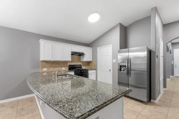a kitchen with stainless steel appliances granite countertop a sink a stove and a refrigerator