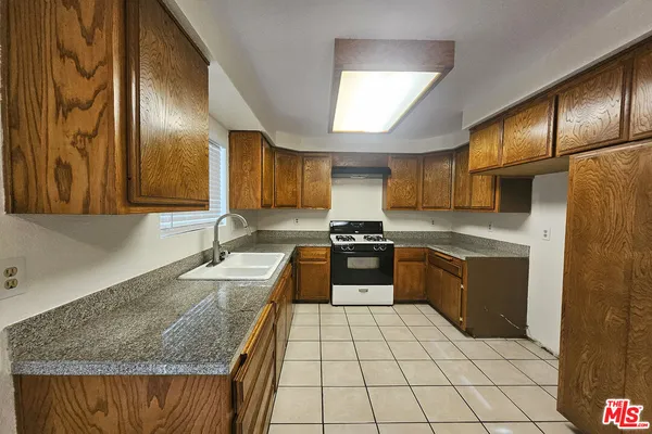 a kitchen with granite countertop stainless steel appliances a sink stove and cabinets