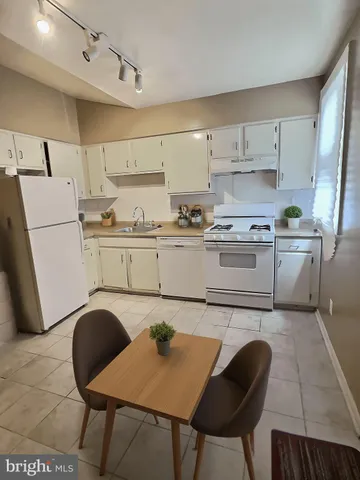 a kitchen with stainless steel appliances granite countertop a table chairs sink and cabinets