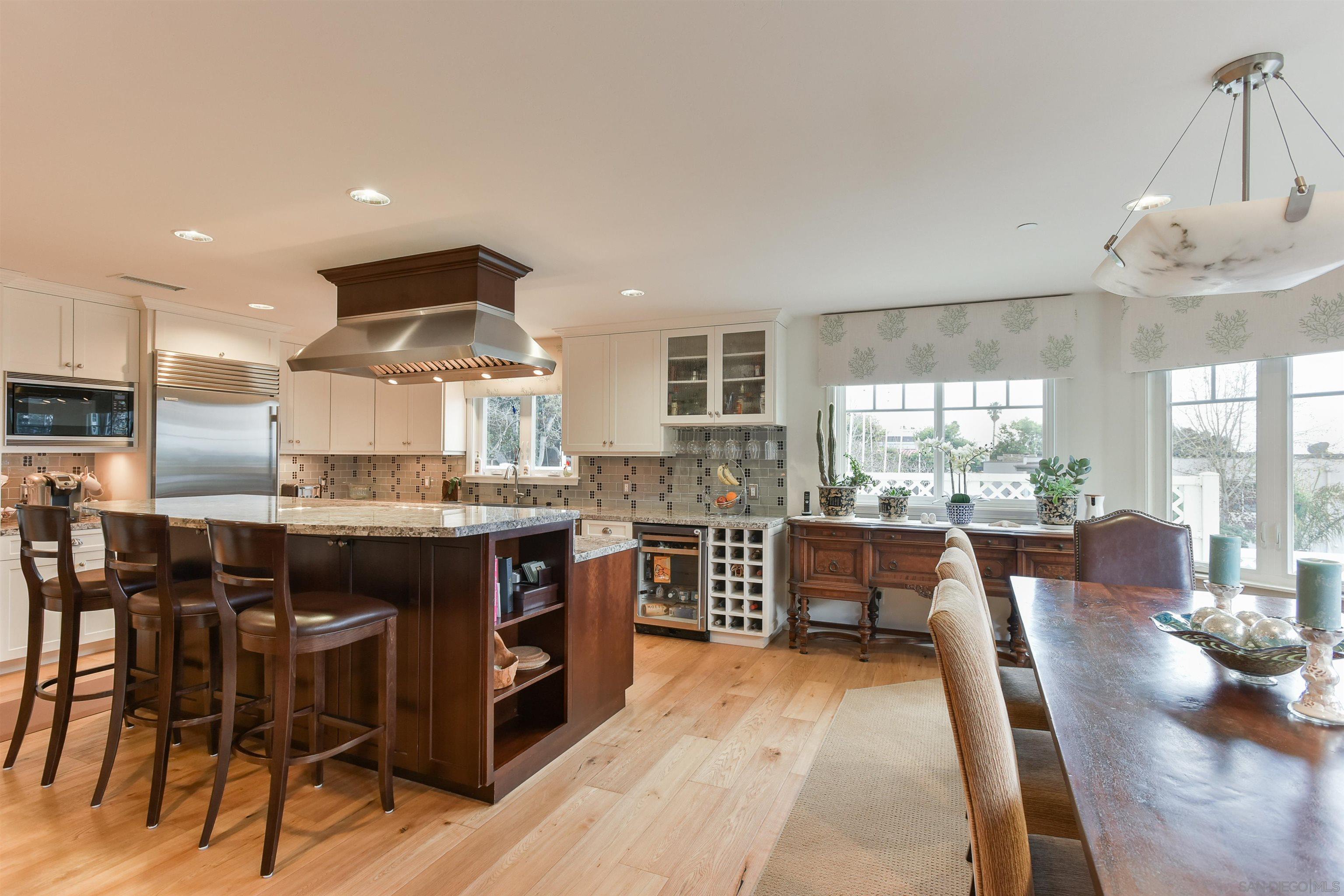 222 Barbara Avenue Solana Beach, CA 92075 - Photo 9 of 37 a kitchen with stainless steel appliances granite countertop a stove top oven a sink dishwasher a dining table and chairs with wooden floor
