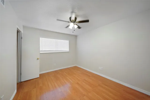 an empty room with a window and a fan
