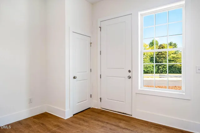 a view of an empty room with wooden floor and a window