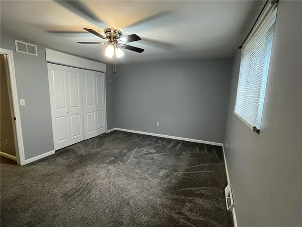 an empty room with a ceiling fan and a window