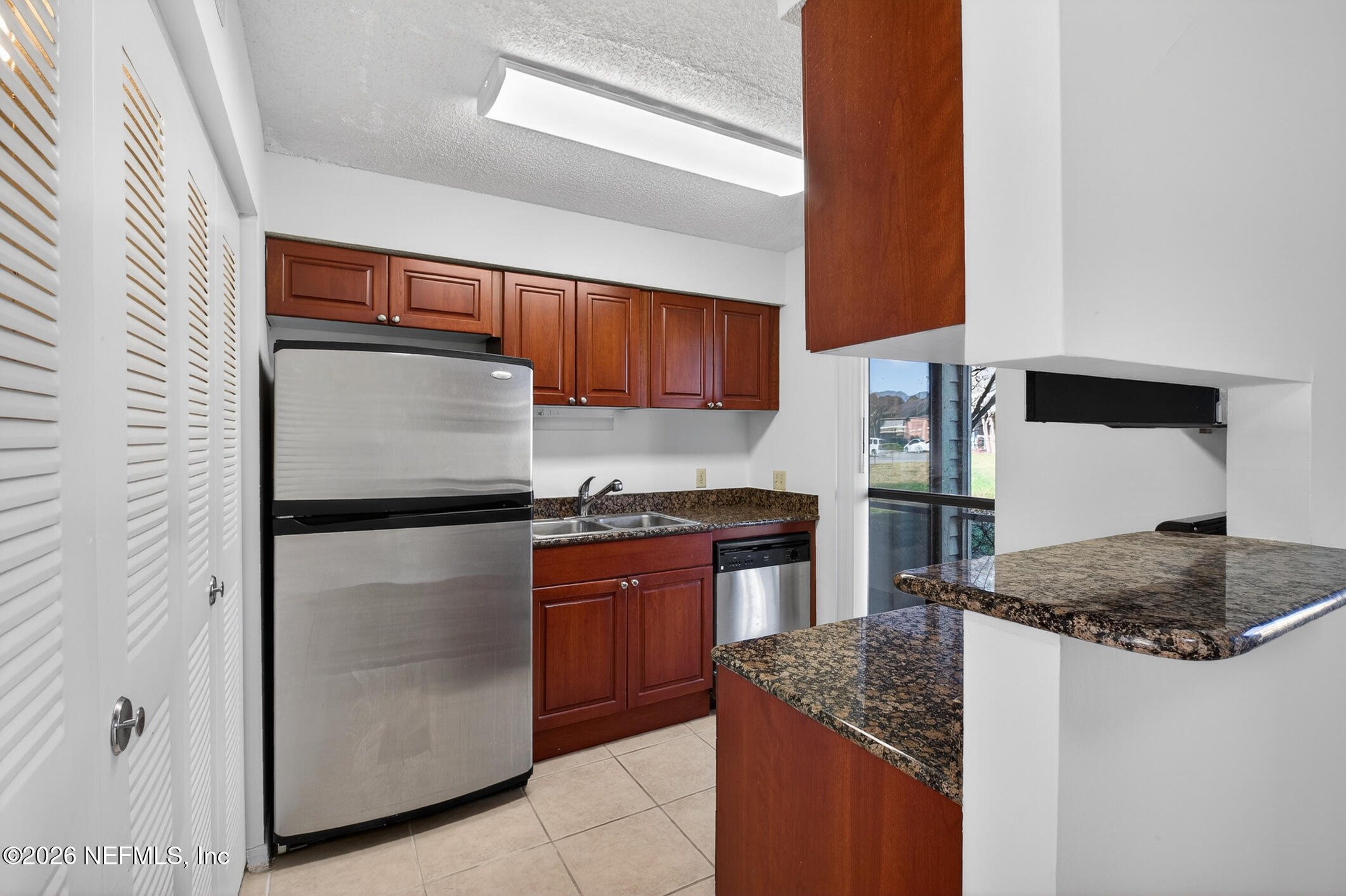 10200 Belle Rive Boulevard, Unit 105 Jacksonville, FL 32256 - Photo 18 of 47 a kitchen with stainless steel appliances granite countertop a refrigerator a stove and a sink with wooden cabinets