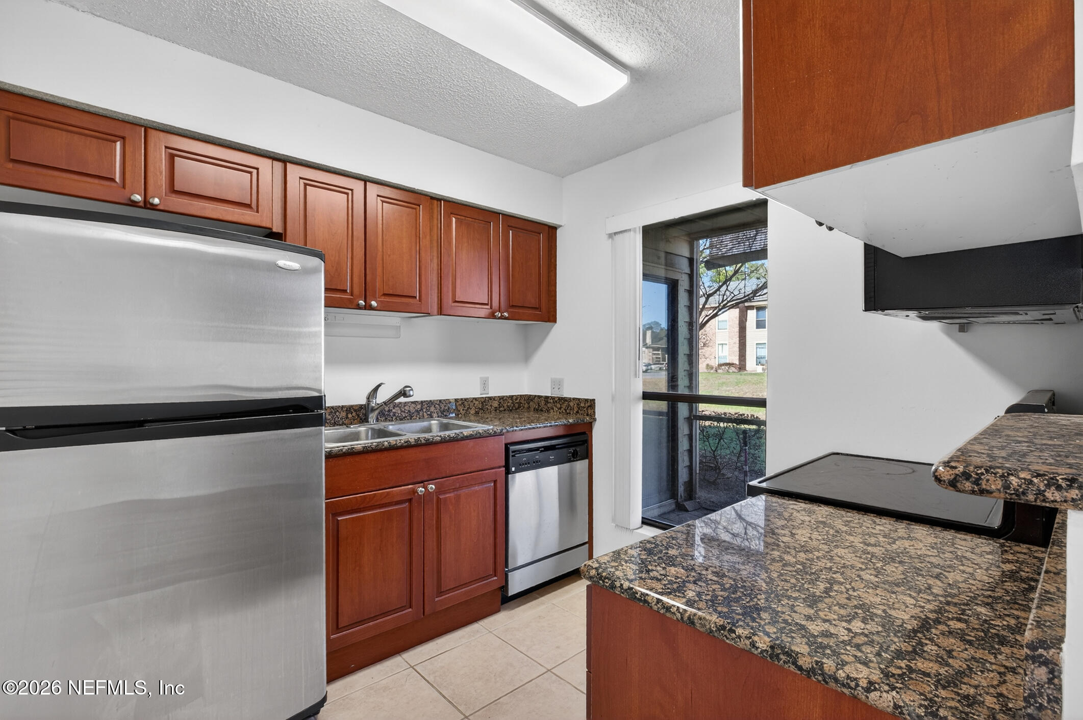 10200 Belle Rive Boulevard, Unit 105 Jacksonville, FL 32256 - Photo 19 of 47 a kitchen with stainless steel appliances granite countertop a refrigerator a stove and a sink with wooden floors