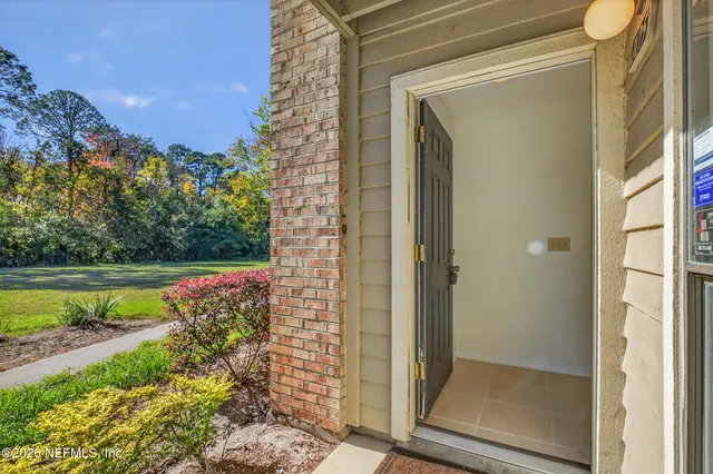 a view of an empty room with wooden floor fireplace and a window