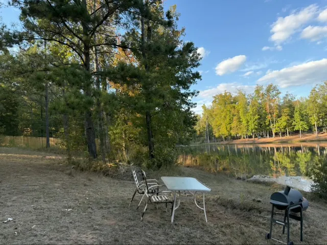 a view of a lake with a table and chairs under an umbrella