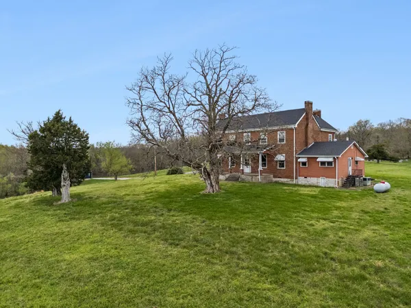 a view of a big house with a big yard and large trees
