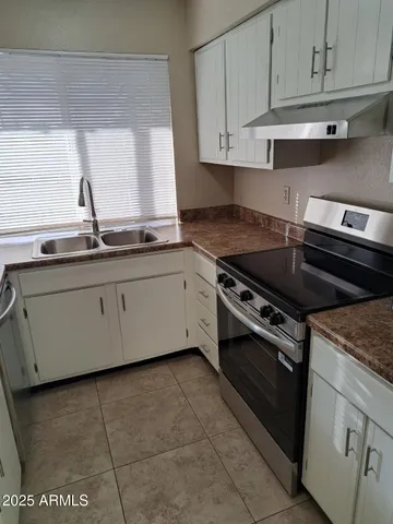a kitchen with stainless steel appliances granite countertop a stove a sink and white cabinets