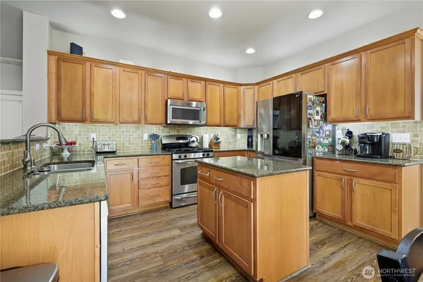 a kitchen with stainless steel appliances granite countertop a stove a sink and a microwave