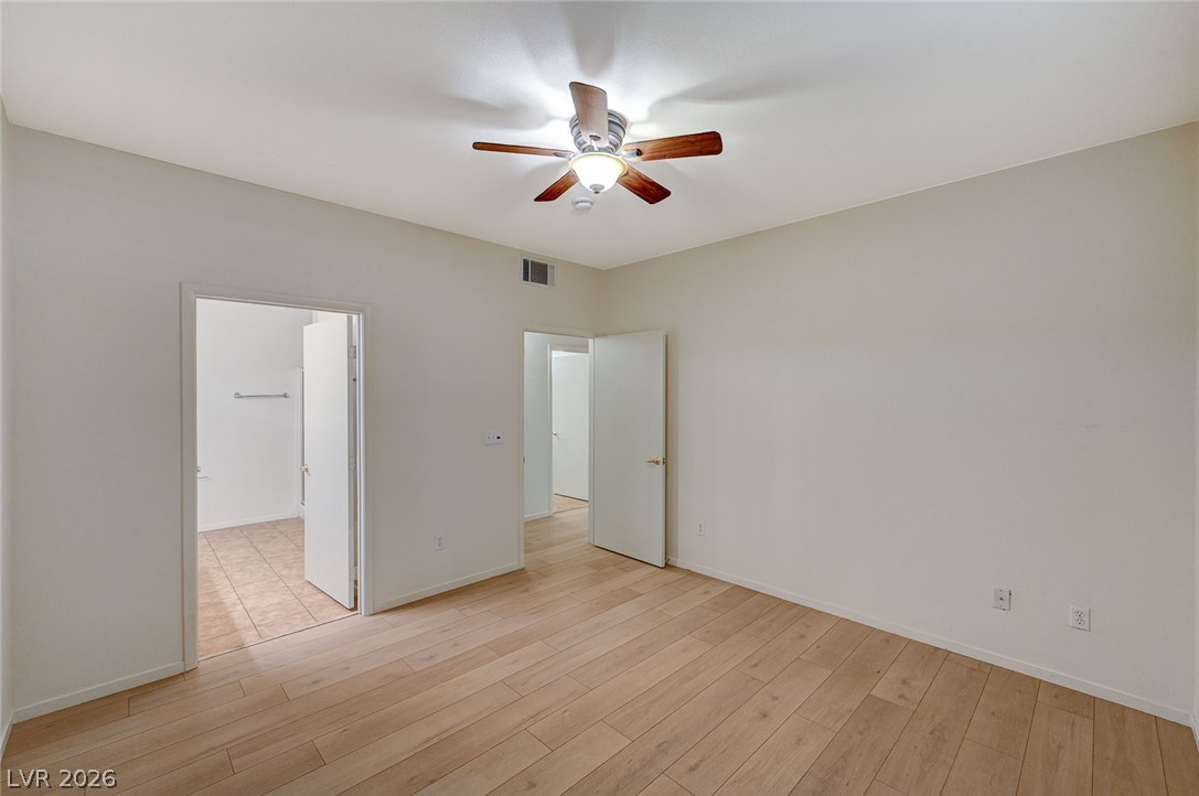 9050 West Warm Springs Road, Unit 1147 Las Vegas, NV 89148 - Photo 24 of 36 Blonde wood flooring spans this airy room, leading to an adjoining space with tiled floors.