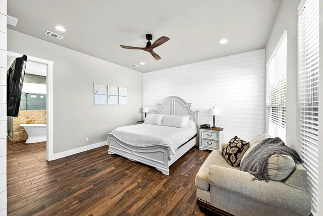 a spacious bedroom with a bed a couch and a large window