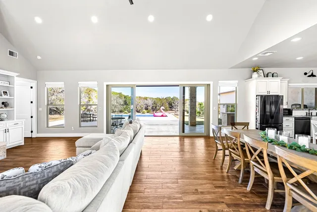 a living room with furniture large window and wooden floor