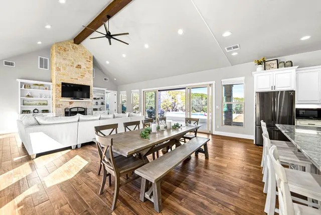 a large dining hall with stainless steel appliances granite countertop a stove top oven a dining table and chairs with wooden floor