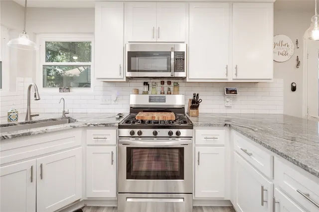 a kitchen with cabinets stainless steel appliances a sink and a stove