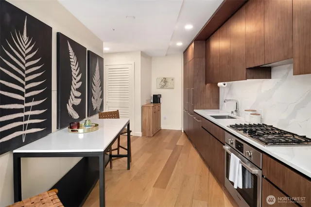 a kitchen with stainless steel appliances granite countertop a stove a sink dishwasher and cabinets with wooden floor