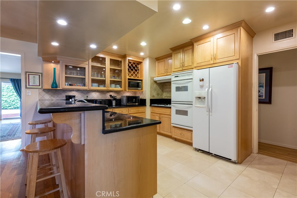 1401 Hackett Avenue Long Beach, CA 90815 - Photo 17 of 48 a kitchen with stainless steel appliances kitchen island granite countertop a refrigerator and a stove top oven