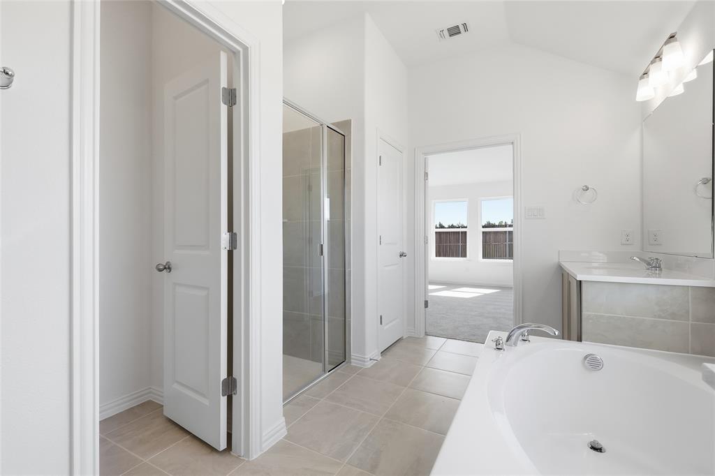 2529 Rivers W Road Anna, TX 75409 - Photo 25 of 40 Bathroom featuring a built-in soaking tub, a glass-enclosed shower, a double vanity with a mirrored backsplash, and light-toned tile flooring