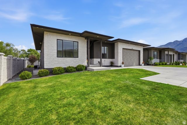 653 East Vandalay Lane Draper, UT 84020 - Photo 2 of 61 Modern single-story residence featuring a flat roofline, stone facade, black-framed windows, an attached garage with a textured door, and a concrete driveway