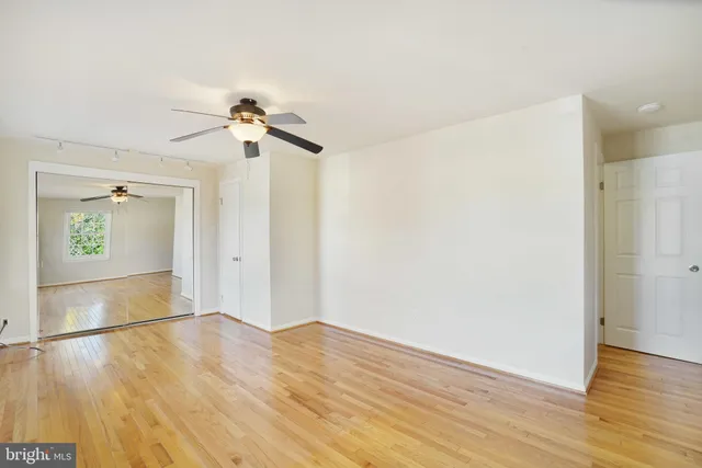 a view of a room with wooden floor and a ceiling fan