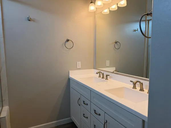 a bathroom with a granite countertop sink a mirror and shower