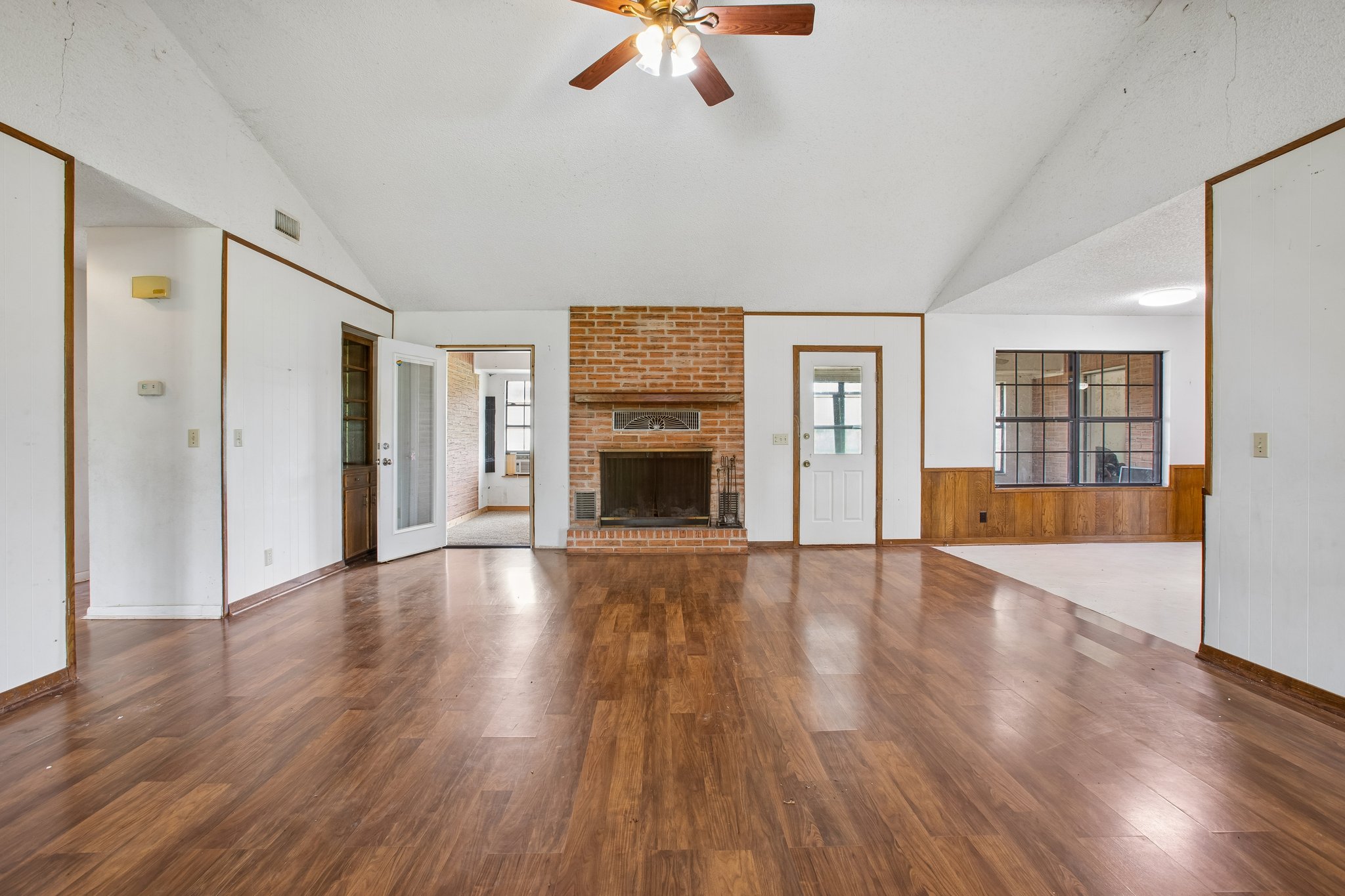 406 Monkey Road Elgin, TX 78621 - Photo 5 of 39 Expansive interior featuring wood-finish flooring, a brick fireplace, vaulted ceilings, and a ceiling fan