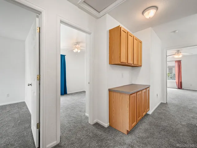 an empty room with chandelier fan and windows