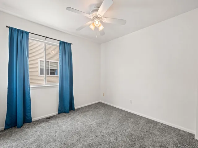 an empty room with closet and a ceiling fan
