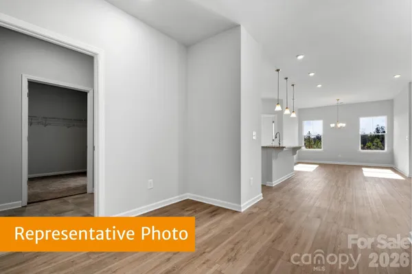 a view of kitchen and empty room with wooden floor