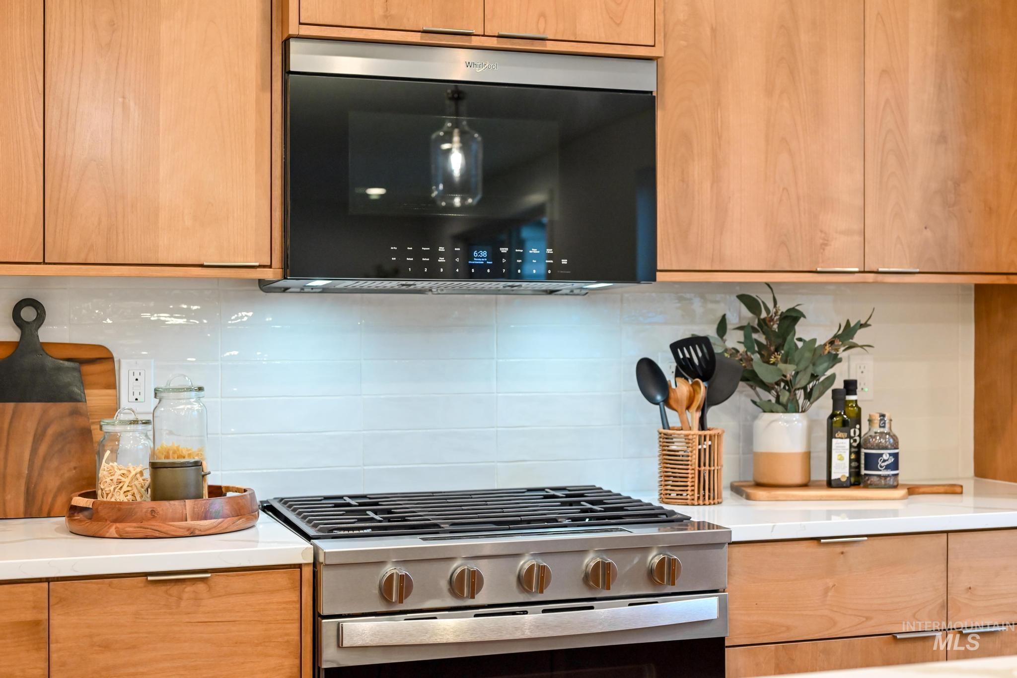 2087 West Gelding Street Middleton, ID 83644 - Photo 15 of 41 Kitchen with stainless steel gas stove, decorative backsplash, black microwave, light stone countertops, and modern cabinets