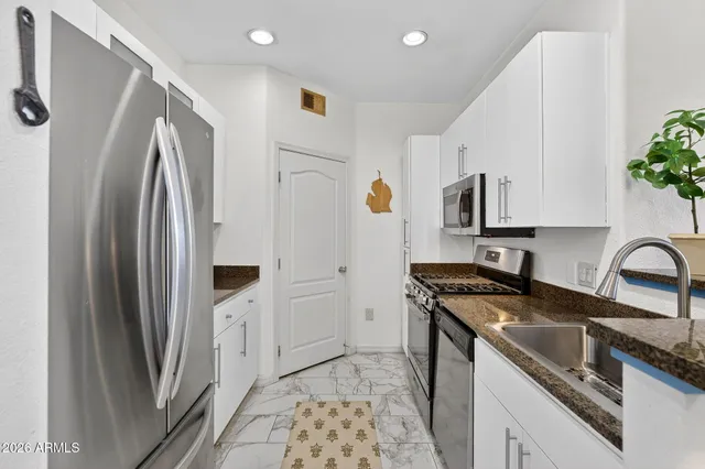 a kitchen with stainless steel appliances a refrigerator sink and white cabinets