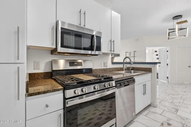 a kitchen with stainless steel appliances granite countertop a sink stove and microwave