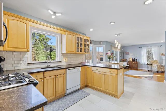 a kitchen with stainless steel appliances granite countertop a stove top oven a sink a dining table and chairs
